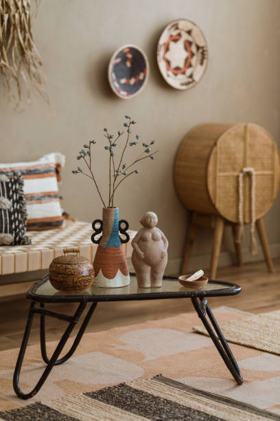 istock Interior design of elegant boho composition with mock up poster frame, modern beige sofa, brown pillow, elegant wooden stand, glass vase with dried flowers, patterned carpet, books and personal accessories. Home decor. Template. 2177389385