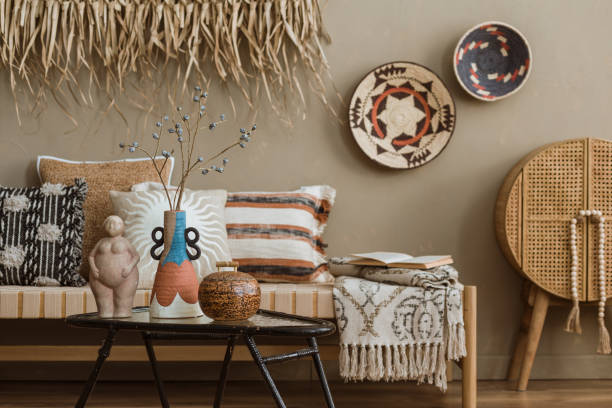 istock Interior design of elegant boho composition with mock up poster frame, modern beige sofa, brown pillow, elegant wooden stand, glass vase with dried flowers, patterned carpet, books and personal accessories. Home decor. Template. 2177389422