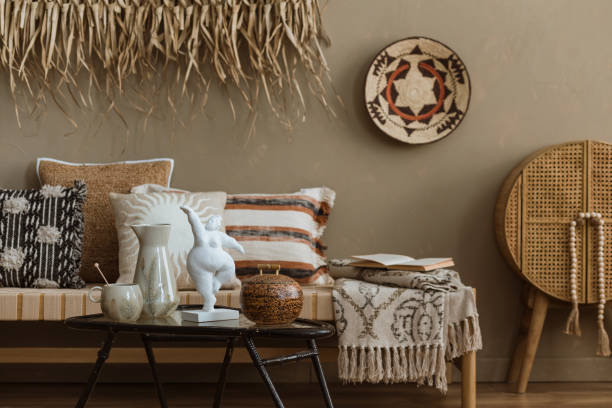 istock Interior design of elegant boho composition with mock up poster frame, modern beige sofa, brown pillow, elegant wooden stand, glass vase with dried flowers, patterned carpet, books and personal accessories. Home decor. Template. 2177389470