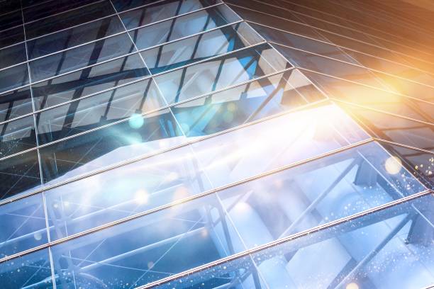 istock A low angle view of a glass building, with a bright sun in the background. 2177391415
