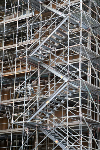 Germany, Berlin, Neukoelln, August 26, 2025 - Scaffolding on a yellow house wall