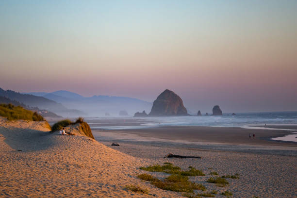 istock Young woman explores empty beach at sunrise, distant view 2177395285