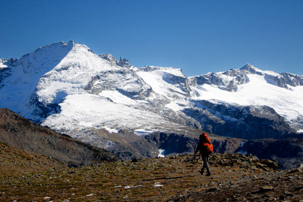 istock Backpacker hikes mountain ridge below snowcapped mountain 2177395892