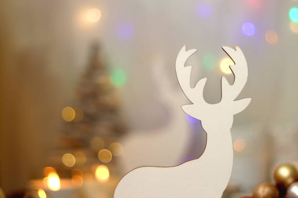 Various Christmas decorations, lit candles, cup of tea or coffee, cookies, books, presents and soft blanket on the table. Holiday hygge at home. Selective focus.