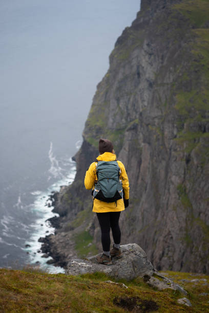 istock An adventurous female stands at a cliffs edge, surrounded by a stunning, misty landscape. 2177398602