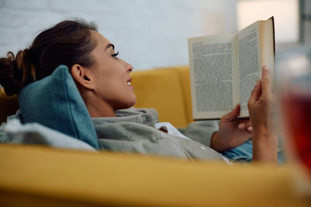 istock Smiling woman reading book while enjoying in relaxing day at home. 2177400603