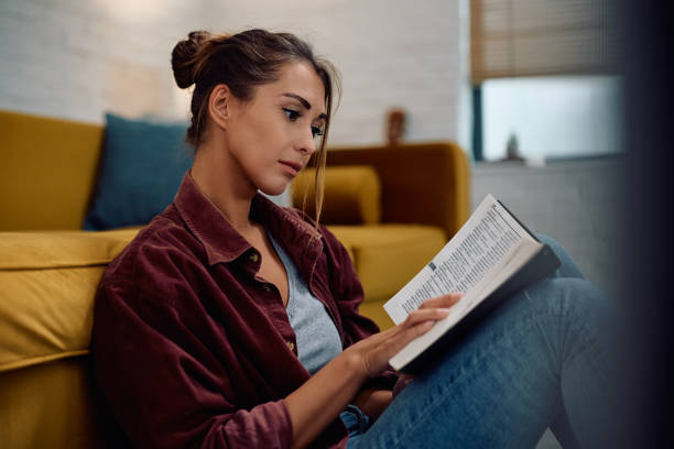istock Young woman studying from a book at home. 2177400990