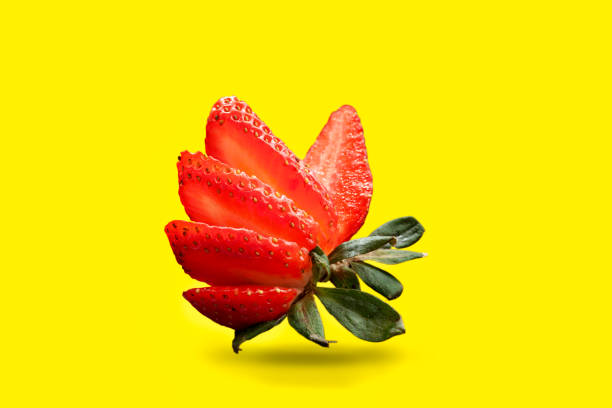 a single cut strawberry isolated on a yellow background