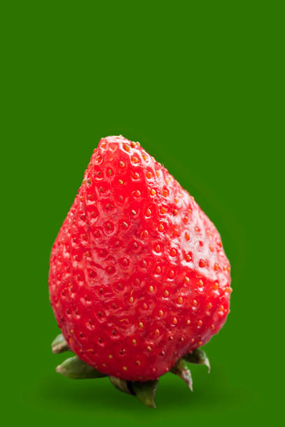 a single cut strawberry isolated on a yellow background