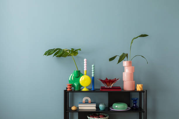 istock Colorful composition on blue wall with black shelf, design accessories, and decorations vases with leaf, candels and copy space. Home decor. Template. 2177401995