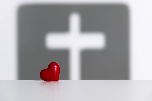 Religious cross shadow and red heart on white background