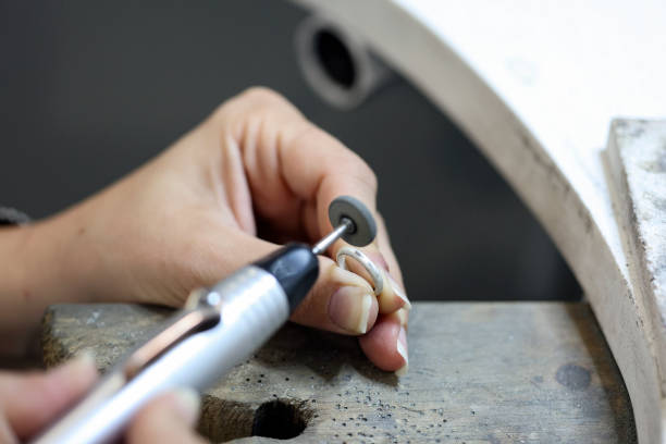 Close-up of an unrecognizable female Caucasian jeweler polishing a ring in her workshop.