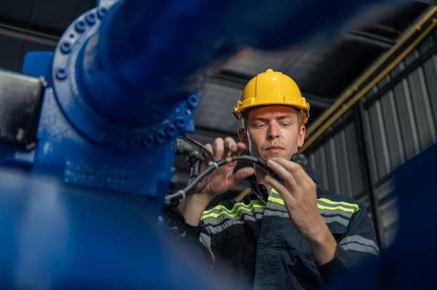 istock Engineer standing by robotic arm and operating machine in industry factory, technician worker check for repair maintenance electronic operation 2177423452
