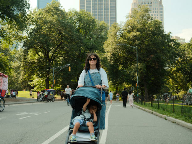 istock Mother pushing baby stroller in central park new york 2177426509