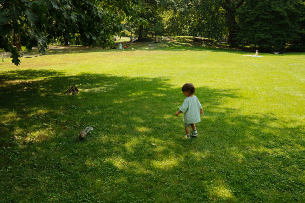 A group of smiling children relaxing on bright green grass in a sunny park, showcasing friendship, playfulness, and carefree outdoor moments. Features diverse kids including an Asian boy and a red-haired girl.
