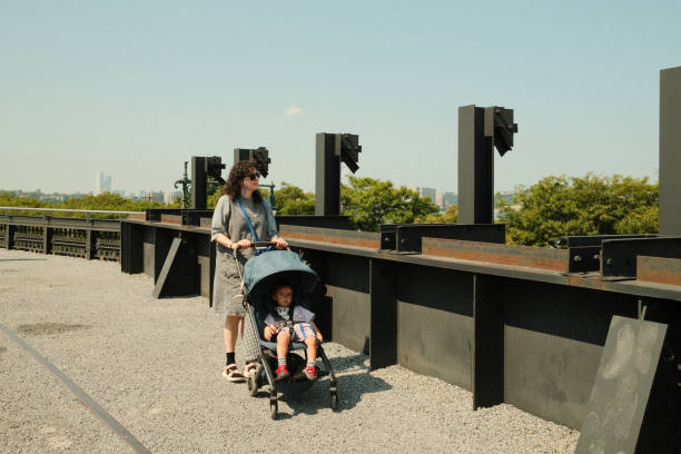 Mother happily pushes her baby in a stroller on a sunny city rooftop, enjoying the urban view and fresh air together