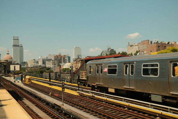 Subway train is arriving at a station with the cityscape in the background on a sunny summer day