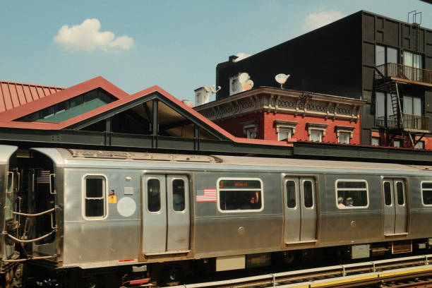 Subway train is arriving at a station with passengers waiting on the platform on a sunny day