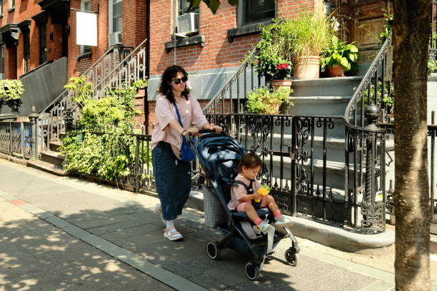 istock Mother pushing baby in stroller on sunny sidewalk in brooklyn heights 2177429277