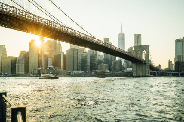 istock Sun shining under brooklyn bridge at sunset with manhattan skyline in background 2177429301