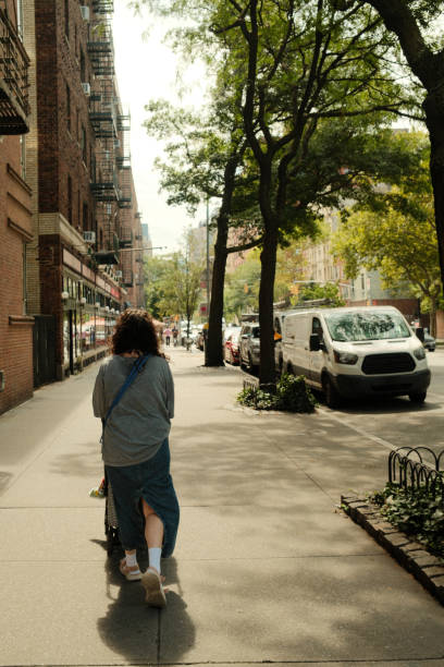 istock Mother pushing stroller on sunny city sidewalk in summertime 2177429327