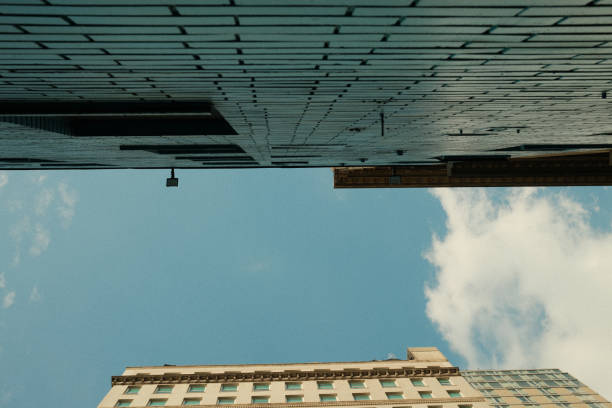 Wide angle view looking up at the blue sky and clouds from between buildings in a city alleyway