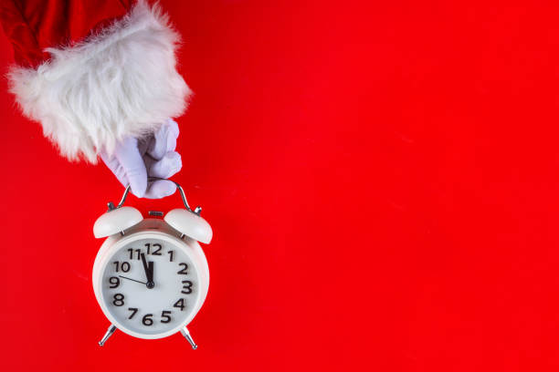 istock Santa Claus hand holding white alarm clock on red background 2177436395