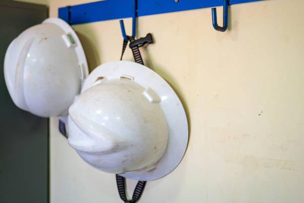 A safety helmet or hardhat, the safety PPE for construction worker is hanging in row. Industrial working equipment object, close-up.