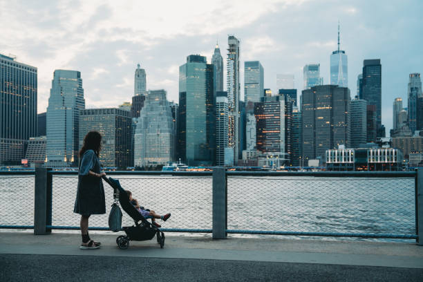 istock Mother pushing stroller along river with city skyline in background 2177437968