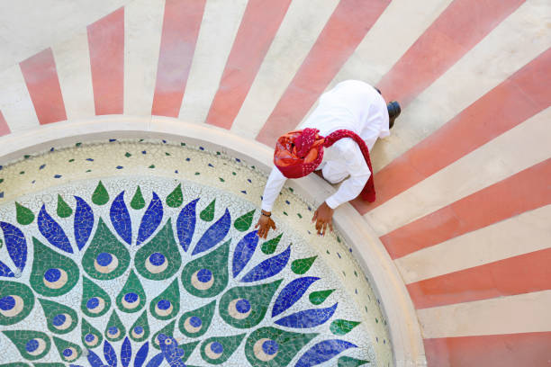 India Jaipur, Rajistan.   hotel worker cleaning  pond.