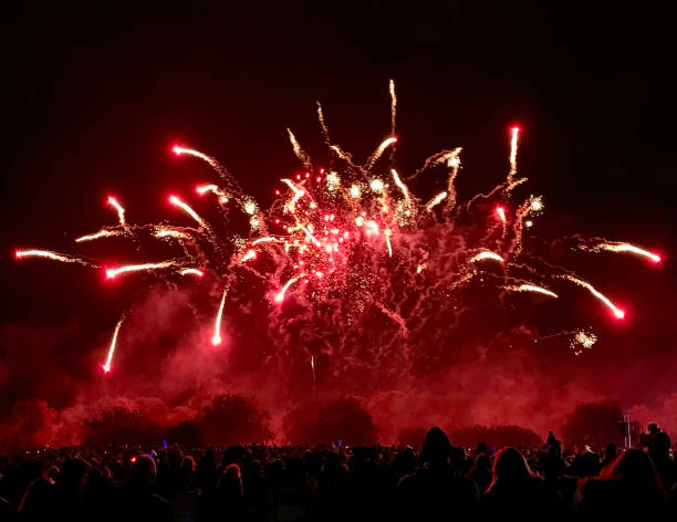 istock Fireworks exploding on a dark bonfire night above a crowd of people watching the display in a British park. 2177442349