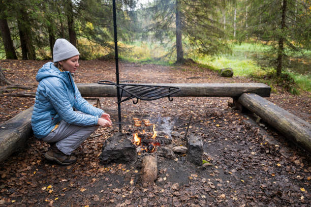 istock woman in the blue jacket cooking on a campfire in the forest 2177442481