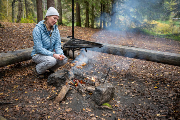 istock woman in the blue jacket cooking on a campfire in the forest 2177442797