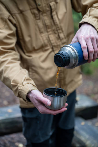 istock Man pouring hot tea from thermos into a cup in the forest 2177443157