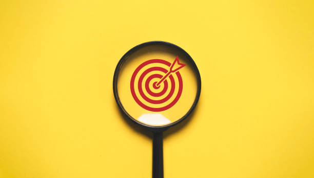istock Red Target board inside of magnifier glass for focus business objective on yellow background and copy space. 2177445910