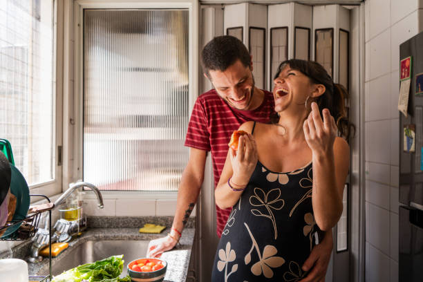 Couple talking and eating fruit in domestic kitchen