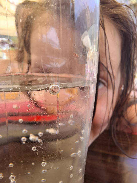 Close-up of a child looking through glass of sparkling water during summer day at the restaurant