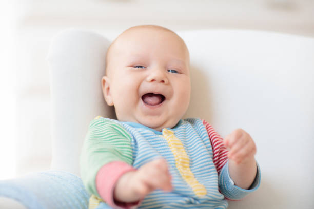 A 5 month old baby boy on his belly looking up and smiling.