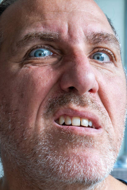 Close up of funny and weird, mimic and face expression of a man with blue eyes and stubble.