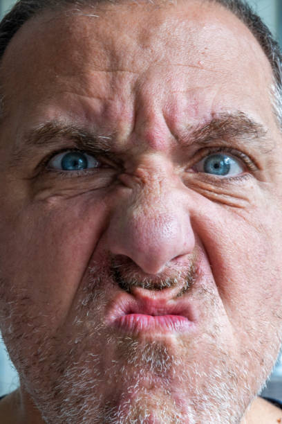 Close up of funny and weird, mimic and face expression of a man with blue eyes and stubble.