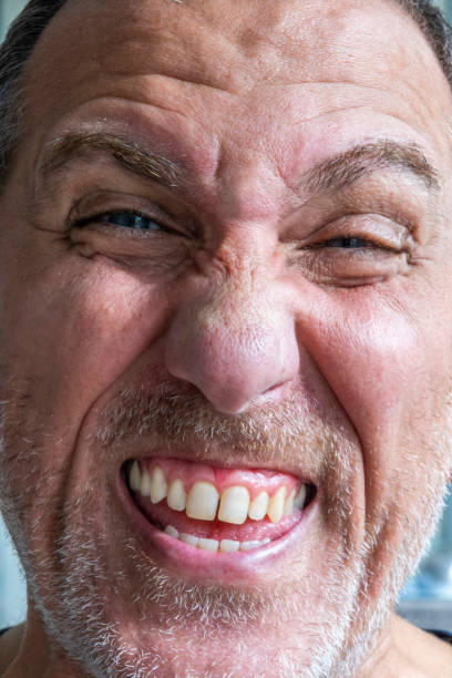 Close up of funny and weird, mimic and face expression of a man with blue eyes and stubble.