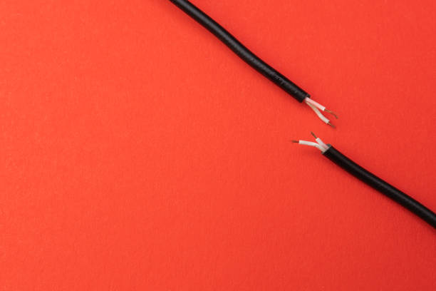 Two ends of a torn cable with a copper core, on a red background. Broken cable requiring repair. Disconnection concept
