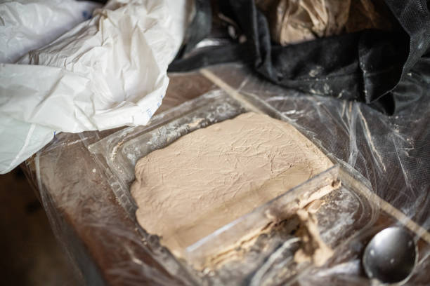 This is a close up of a slab of clay on a makeshift workstation setup on a table at home viewed from an overhead perspective.