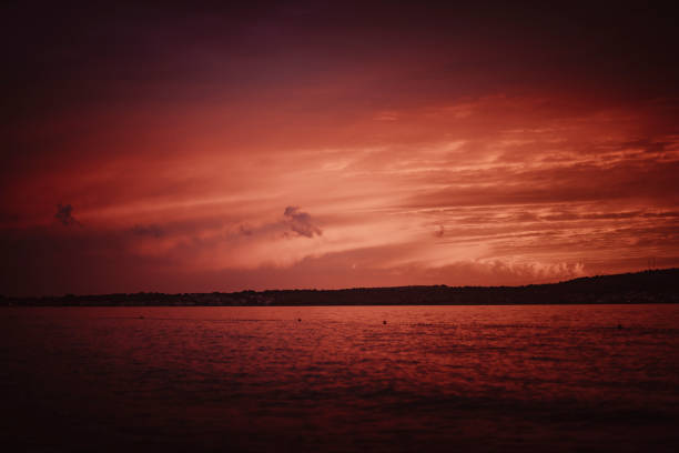 Scenic view of calm bay and clouds at sunset