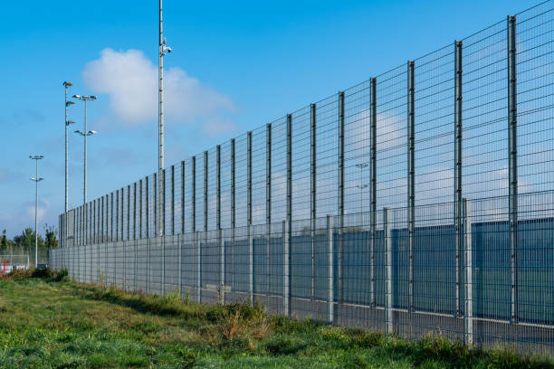 istock High security fence surrounding a facility on a clear sunny day 2177458925