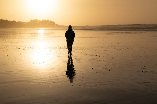 istock Woman walks down beach at sunset 2177459222