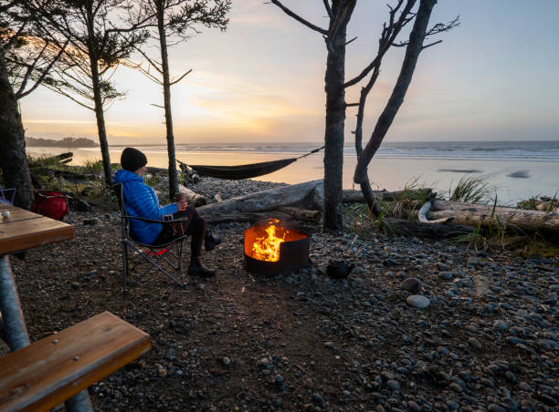 istock Woman relaxes by campfire and looks at ocean 2177459673