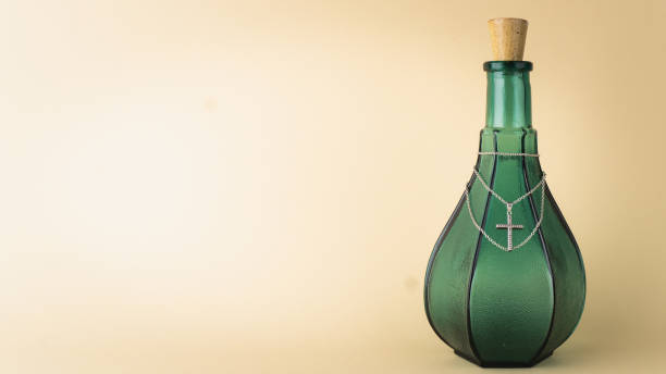 Green glass bottle with a cross necklace. Place for text left side.