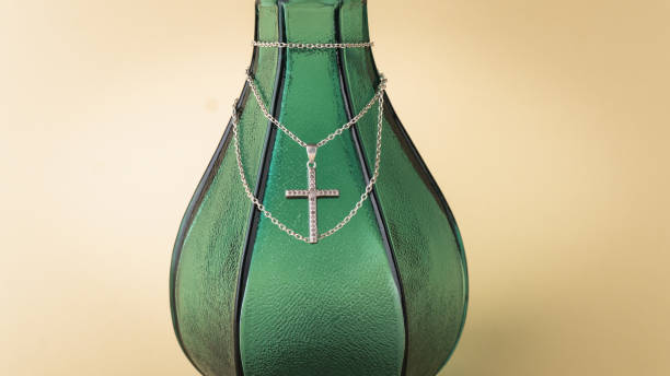 Green glass bottle with a cross necklace. Close up picture.