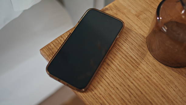 Closeup smartphone wooden table in ambient bedroom setting. Locked smart device